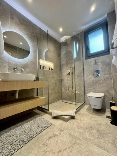 a bathroom with a shower and a sink and a toilet at Trinity Pool Villas GOLD in Iraklitsa