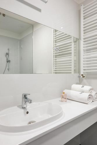 a white bathroom with a sink and a mirror at Dom Zdrojowy CECHINI in Żegiestów