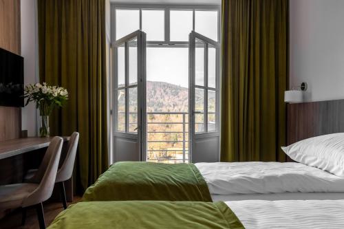 a bedroom with a bed and a large window at Dom Zdrojowy CECHINI in Żegiestów