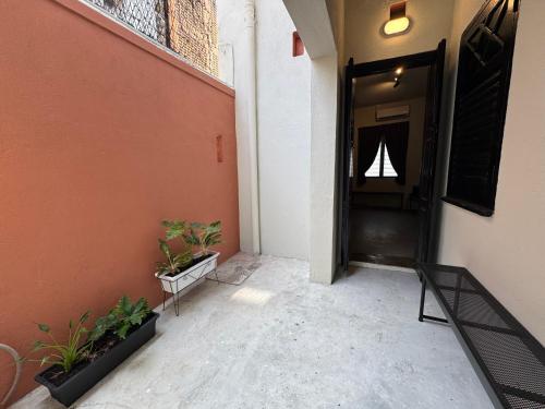 a hallway of a building with a black door and plants at Miner's House Ipoh in Ipoh