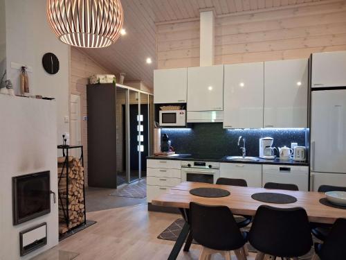 Una cocina con gabinetes blancos y una mesa y sillas. en Kekäle, en Syöte
