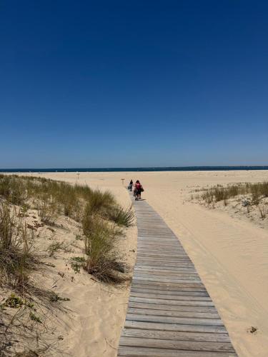 Eine Promenade am Strand mit Leuten, die darauf laufen. in der Unterkunft T3 en RDC avec jardin et 1 place de parking in Soulac-sur-Mer