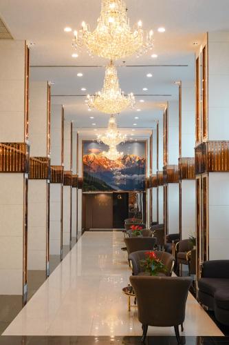 a lobby with chandeliers and a long table with chairs at Golden Empire Suvarnabhumi Hotel in Bang Kew Yai