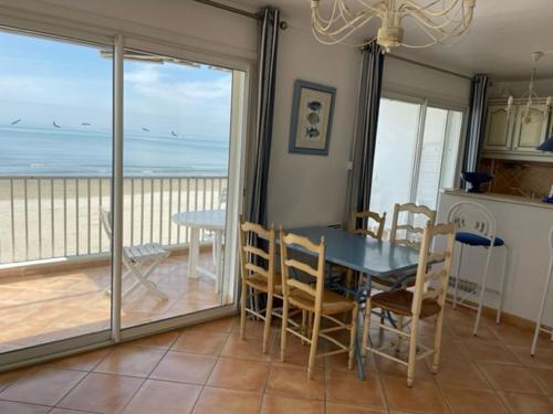 a dining room with a table and a view of the ocean at Résidence C2M Appartement sur plage Grau du Roi in Le Grau-du-Roi