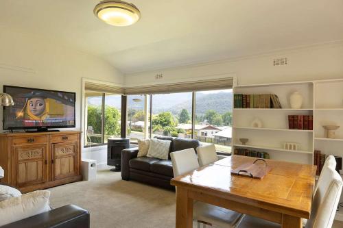 un salon avec une table et un canapé dans l'établissement Cosy Candlewick Cottage - A Mount Beauty Delight, à Mount Beauty