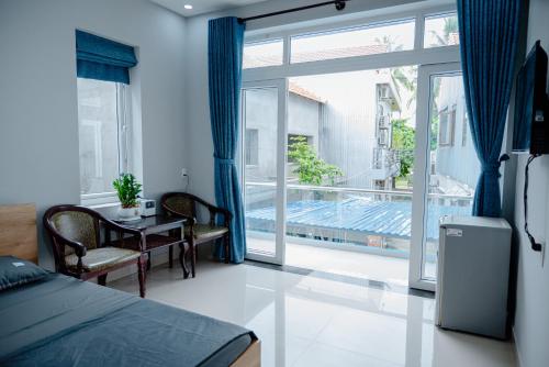 a bedroom with a bed and a table and a large window at Hội An Spirit Homestay in Hoi An