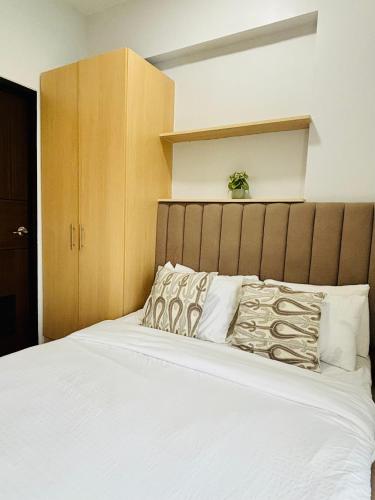 1 dormitorio con 1 cama blanca grande y cabecero de madera en Modern-esque Room at Megaworld, en Iloilo City