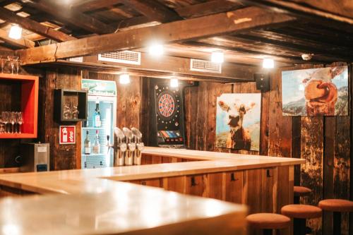 a bar with wooden walls and wooden stools at Hotel Glemmtalerhof in Saalbach Hinterglemm