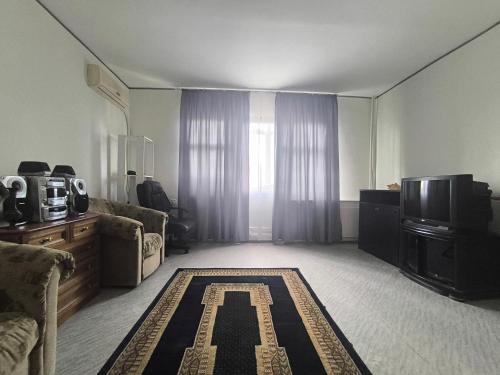 a living room with a tv and a rug with the letter k at Brazeri 2-6-9 in Toshkent-Passajir Bekati