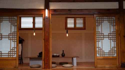 ein Zimmer mit zwei Türen und einem Tisch in einem Zimmer in der Unterkunft Seoul Bukchon Homi Hanok in Seoul