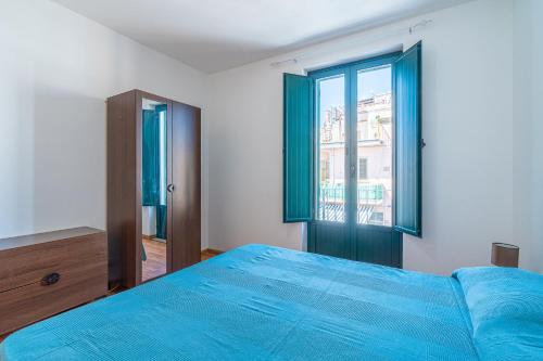 a bedroom with a blue bed and a window at Casa Patrizia in centro a Marzamemi in Marzamemi