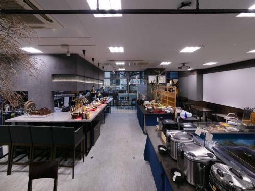 a large kitchen with counters and tables in a restaurant at Nishitetsu Inn Kochi Harimayabashi in Kochi