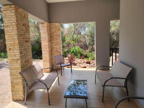 a patio with chairs and a glass table at Bokmakierie Place in Modimolle