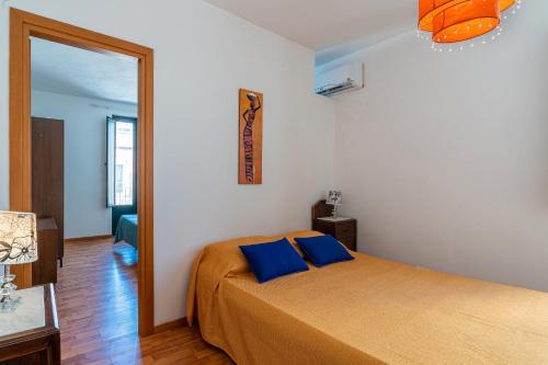 a bedroom with a bed with two blue pillows at Casa Patrizia in centro a Marzamemi in Marzamemi