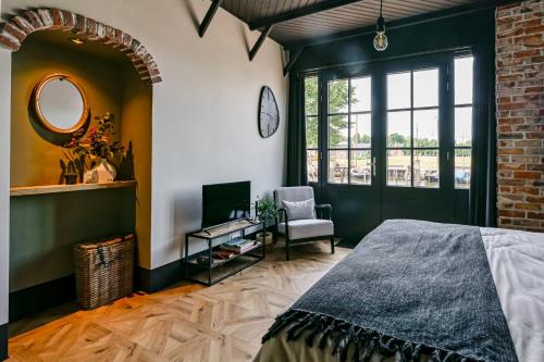 a bedroom with a bed and a chair and a mirror at B & B Havenzicht Elburg in Elburg