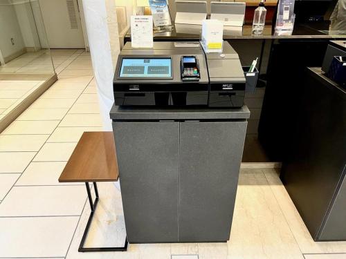 a cash register in a store with a phone on it at Nishitetsu Inn Kochi Harimayabashi in Kochi