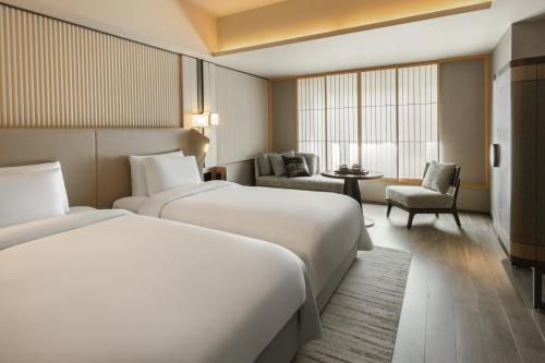 a hotel room with two beds and a chair at Dusit Thani Kyoto in Kyoto