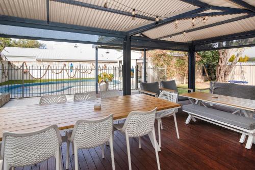 a wooden deck with a wooden table and chairs at Happy Daze Beach House-Pool in Broadwater