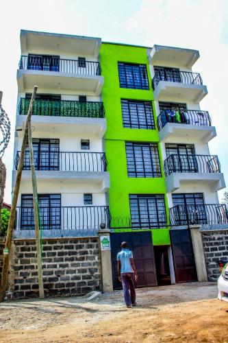 a man standing in front of a green and white building at Essence Urban Homes STUDIO in Kisumu