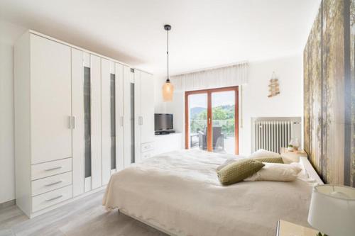 a white bedroom with a large bed and a window at Ferienhaus Burgblick in Hürtgenwald