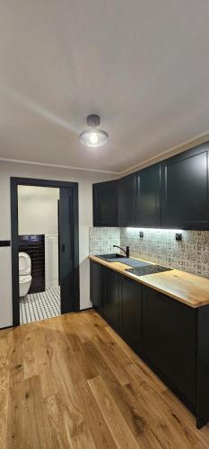 a kitchen with black cabinets and a wooden floor at Apartament przy Poczcie in Koszalin