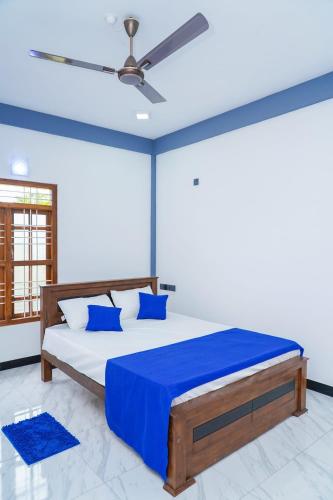 a bedroom with a bed with blue sheets and a ceiling fan at RKM Hotel Uppuveli in Trincomalee