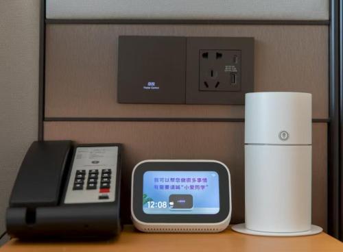 a desk with a phone and a charger and aeper at JI Hotel Beijing Huilongguan West Street全季北京回龙观西大街酒店 in Beijing