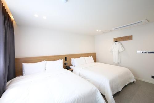 two beds in a room with white sheets at Hotel Onna Haeundae in Busan