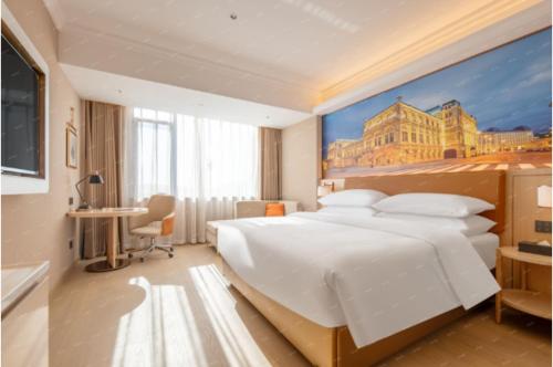a bedroom with a large white bed and a painting at Vienna Hotel Yiwu Heart Branch in Yiwu