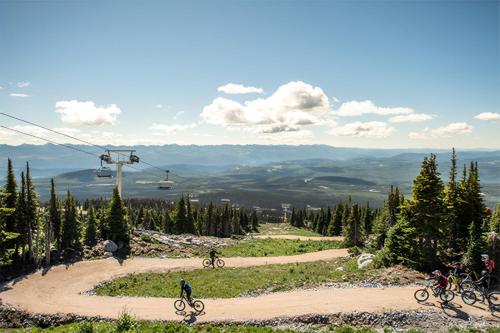 a group of people riding bikes down a dirt road with a ski lift at Winter Escape On Perfection - Ski In Out, Pool & Hot Tub in Big White