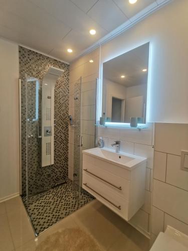 un bagno con lavandino e doccia con specchio di Ferienwohnung Edelweiß a Rust