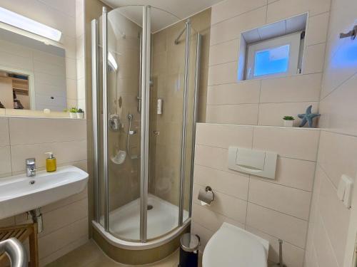 a bathroom with a shower and a toilet and a sink at Feriendorf Rugana - Komfortplus 1-Raum Ferienwohnung mit Terrasse A59 in Dranske
