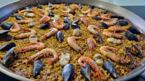 a pan of rice with shrimp and mussels on it at Hello Oliva Beach Roger in Oliva