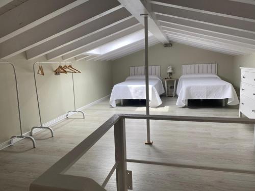 two beds in a room with white walls and wooden floors at House La parada in Nava, Villa de la Sidra in Nava