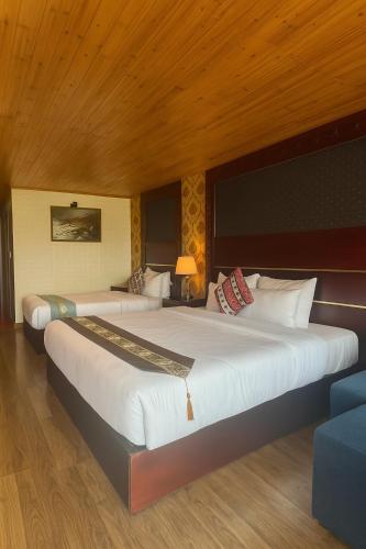 two beds in a bedroom with a wooden ceiling at Sapa Elegance Hotel in Sa Pa