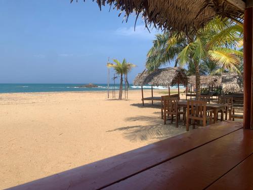a beach with tables and chairs and the ocean at The Tasty Tuna Cabana in Arugam Bay