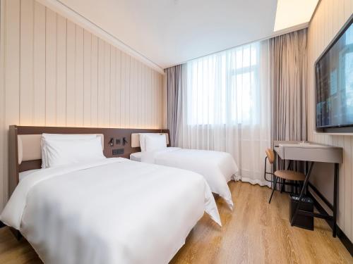 two beds in a hotel room with a flat screen tv at 汉庭北京前门天坛西门酒店 in Beijing