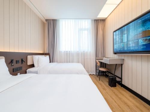 a hotel room with two beds and a flat screen tv at 汉庭北京前门天坛西门酒店 in Beijing