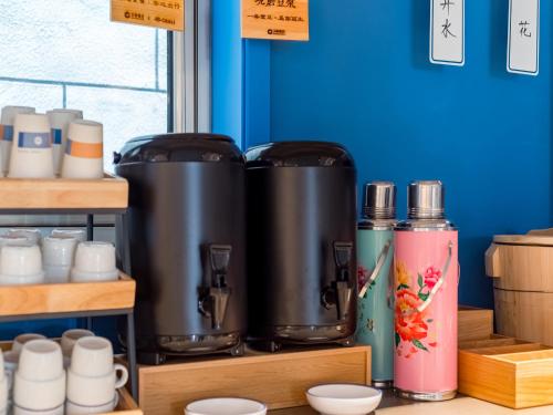 a group of kettles on a shelf with cups at 汉庭北京前门天坛西门酒店 in Beijing