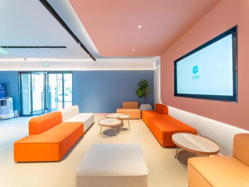 a waiting room with orange furniture and a large screen at 汉庭北京前门天坛西门酒店 in Beijing