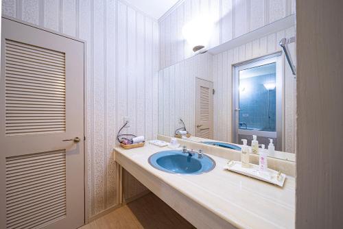 a bathroom with a blue sink and a mirror at Hotel クージー in Okayama