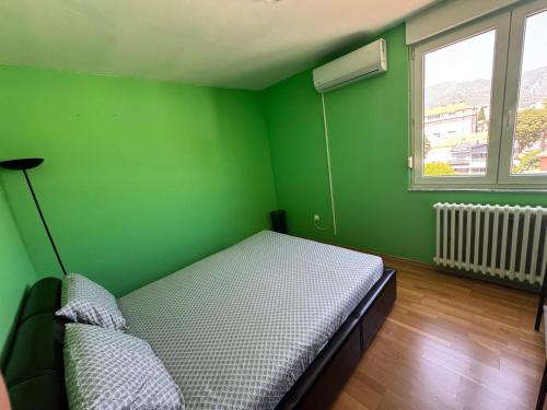 a green room with a bed and a window at Mostar Zen Apartment in Mostar