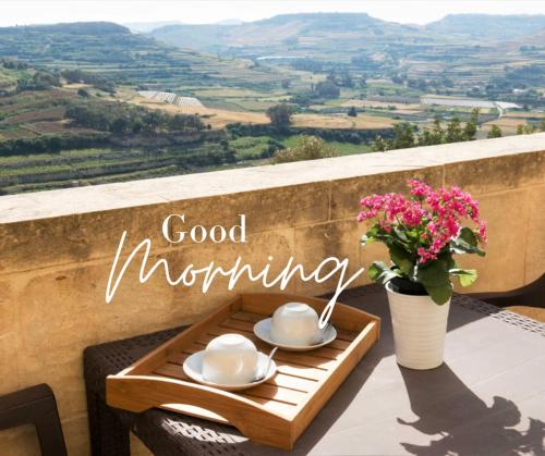 a table with cups and saucers and a vase with flowers at Aurelia Gozo Boutique BnB in Xagħra