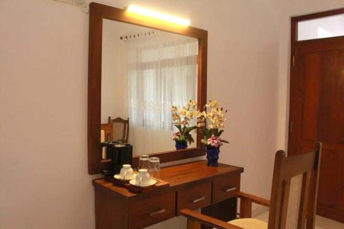 a dressing table with a mirror and flowers on it at Yathramulla Harbour in Bentota