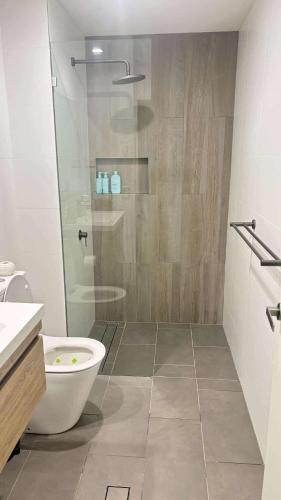 a bathroom with a shower and a toilet and a sink at beach pad in Wollongong