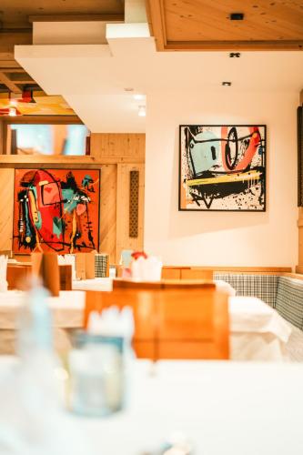 a dining room with paintings on the walls at Hotel Glemmtalerhof in Saalbach Hinterglemm