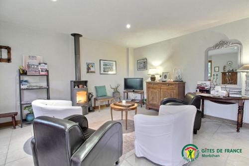a living room with white chairs and a tv at Le verger in Pluneret