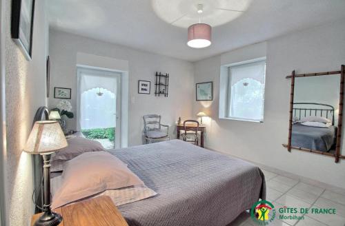 a bedroom with a bed and a table and two windows at Le verger in Pluneret