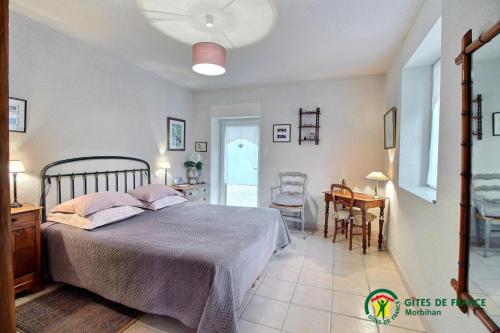 a bedroom with a bed and a table and chairs at Le verger in Pluneret