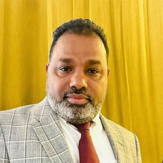 a man with a beard wearing a suit and tie at Gilead Holliday in Tāmarakulam